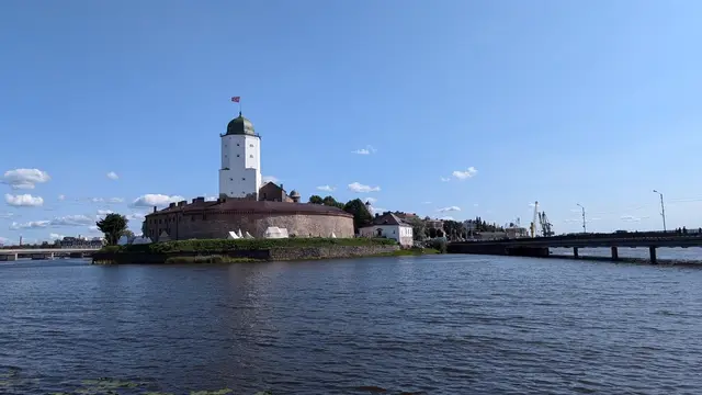 vyborg castle across the water, its white tower and green dome under a summer sky