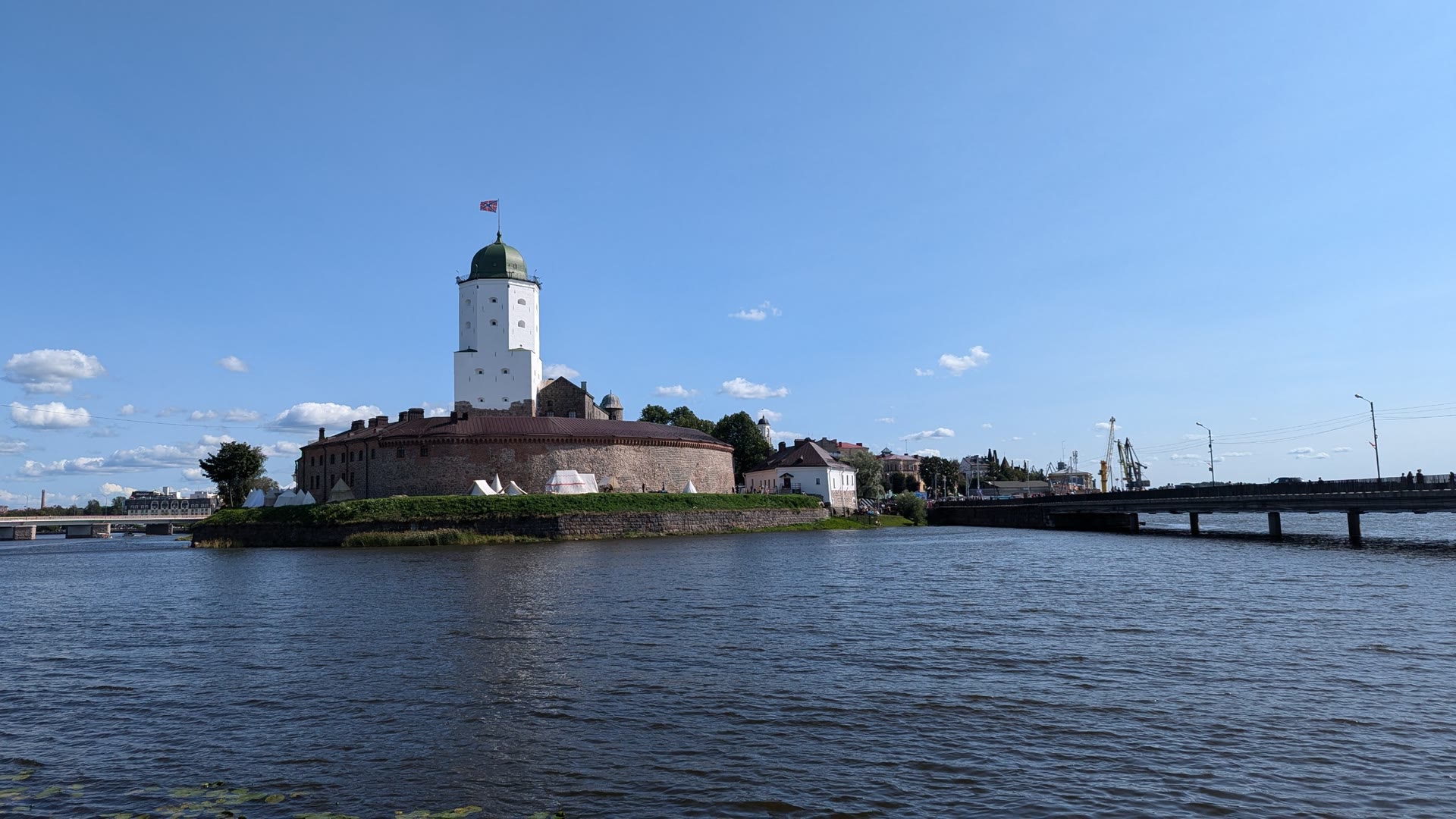 vyborg castle across the water, its white tower and green dome under a summer sky