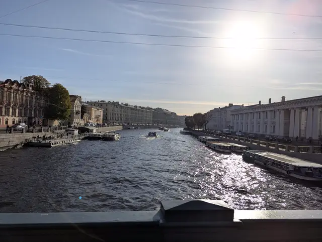the fontanka from a bridge straight into the sun, the water breaking into glare between moored boats