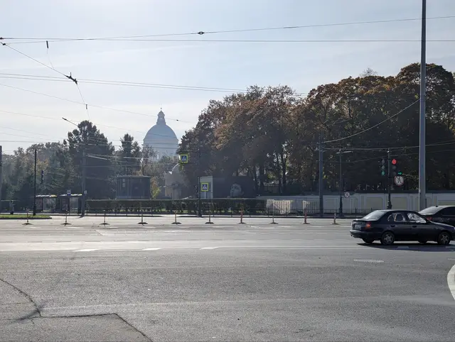 a white cathedral dome rising over a block of autumn trees across an empty road