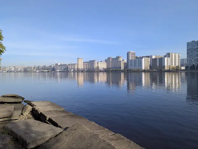 broken granite slabs on the riverbank in the foreground, a long low skyline across the water