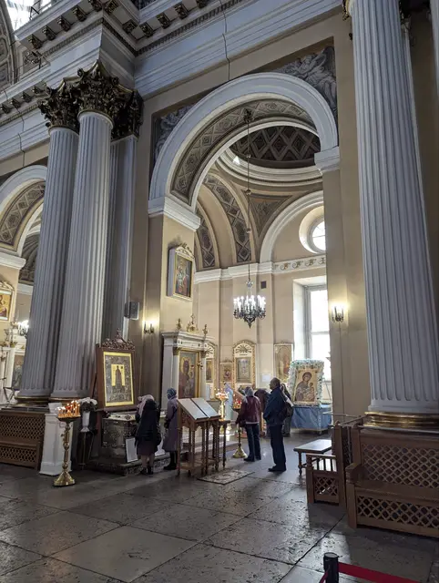 white fluted columns and an arch over a side aisle, a few people standing at the icons