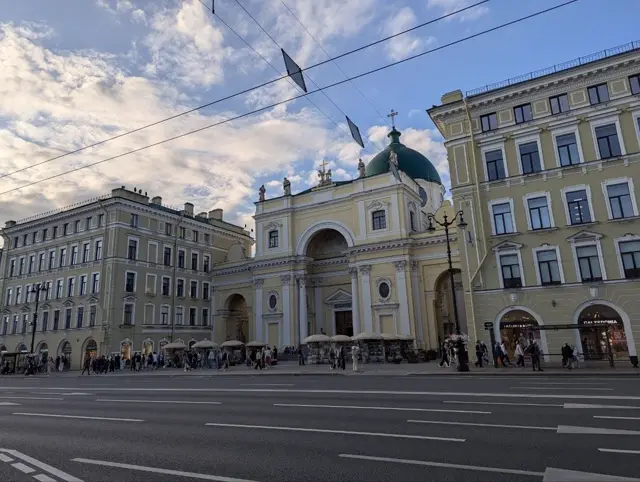 a yellow church with a green dome set back from a busy avenue, book stalls along its forecourt